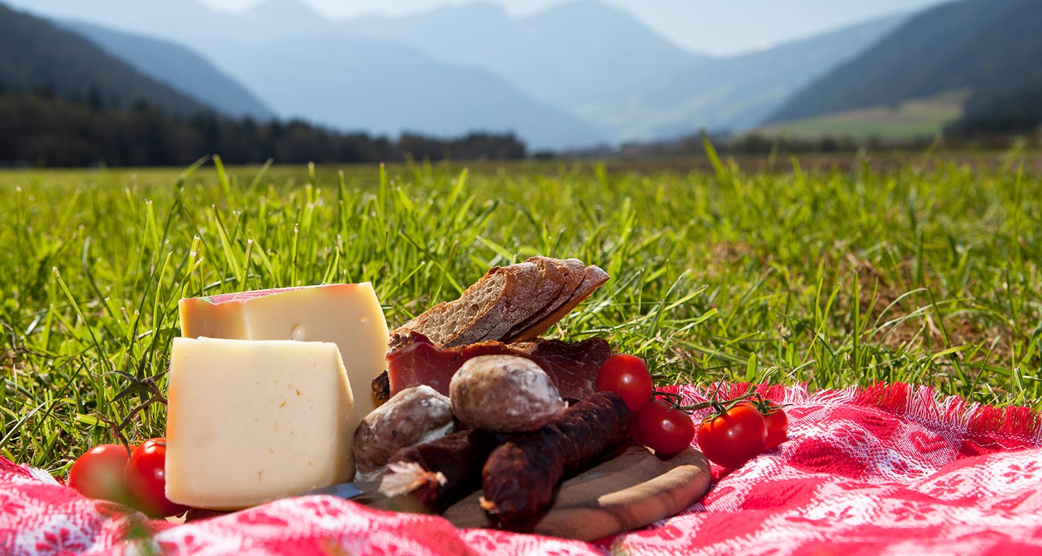Close-up with open picknick basket with cheese, cured meat and cherry tomatoes