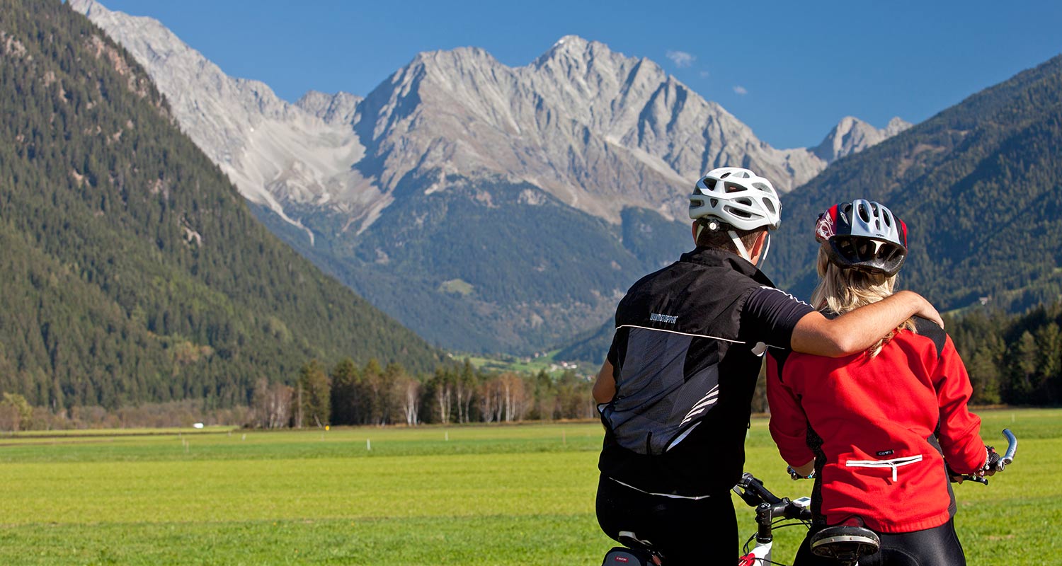 Ciclisti si riposano durante una breve pausa davanti a un panorama di montagna